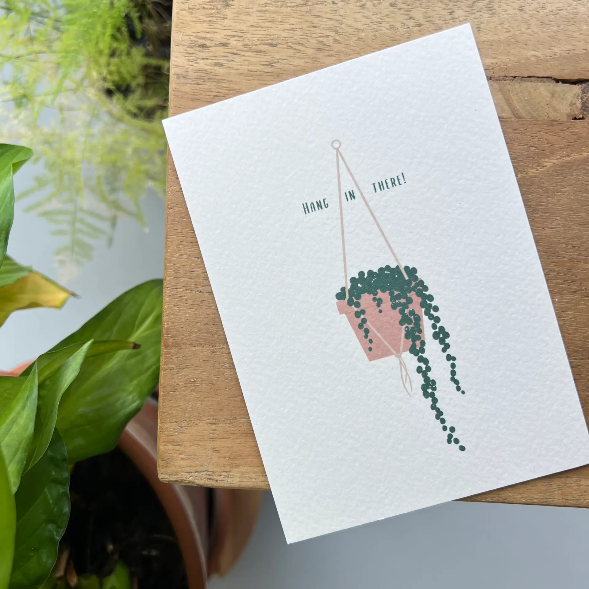Minimalistisch kaartje Hang in There met hangplant illustratie